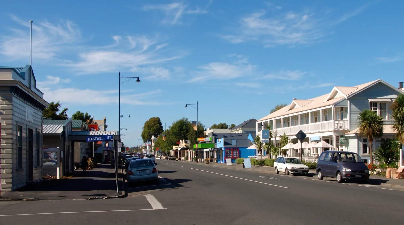 Sunny main street in Greytown lined with historic buildings, parked cars, and a clear blue sky overhead.
