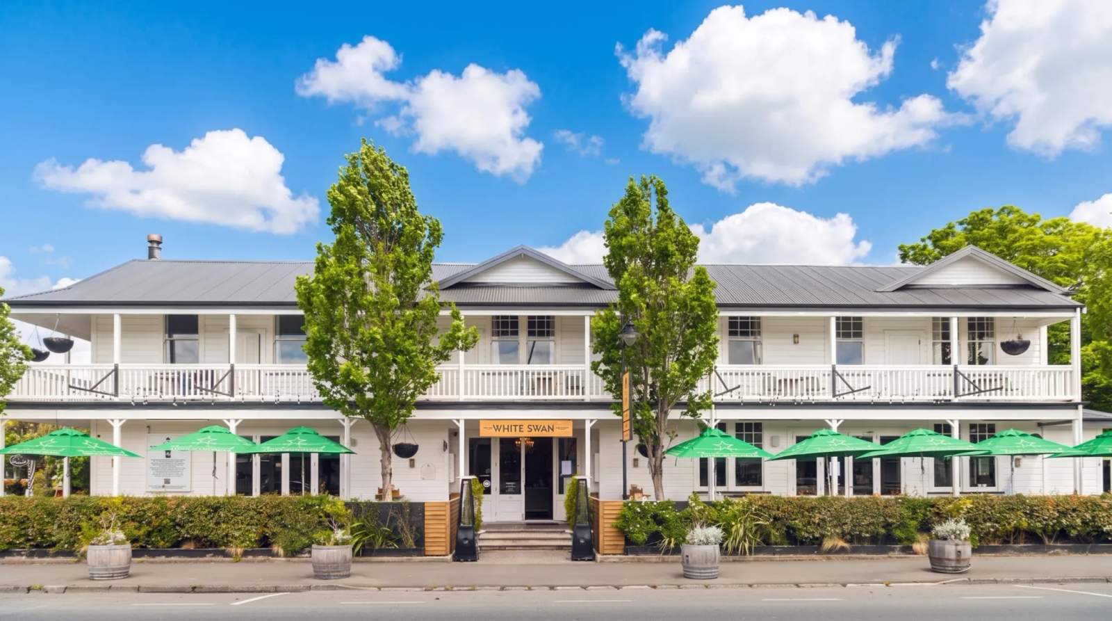 White Swan hotel in Greytown, a large white colonial-style building with green umbrellas and two prominent trees out front.